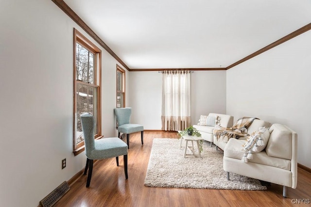 living room featuring visible vents, crown molding, baseboards, and wood finished floors