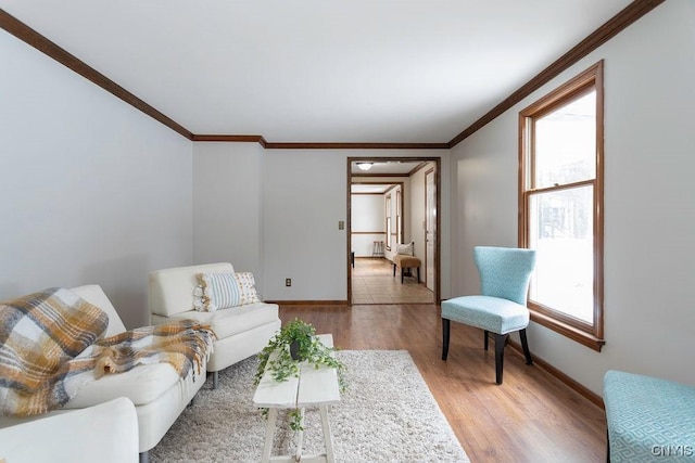 living area with ornamental molding, light wood-style flooring, and baseboards