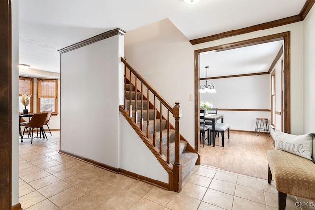 staircase with a notable chandelier, baseboards, tile patterned flooring, and crown molding