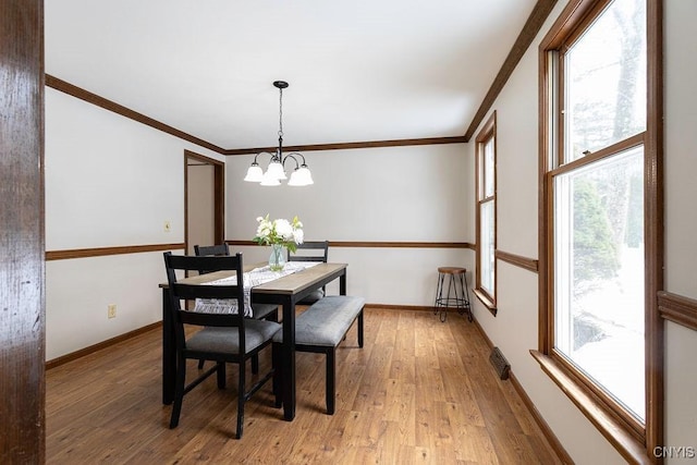 dining space with baseboards, an inviting chandelier, light wood-style flooring, and crown molding