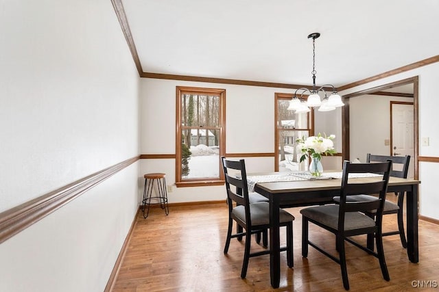 dining area featuring ornamental molding, baseboards, light wood finished floors, and an inviting chandelier