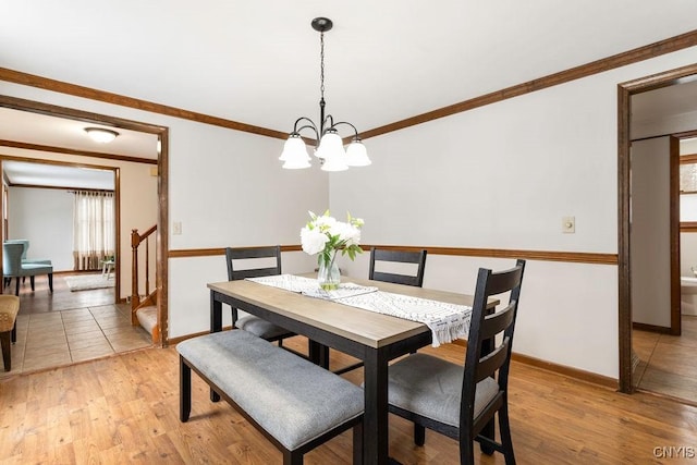 dining space with a chandelier, ornamental molding, light wood-type flooring, and baseboards