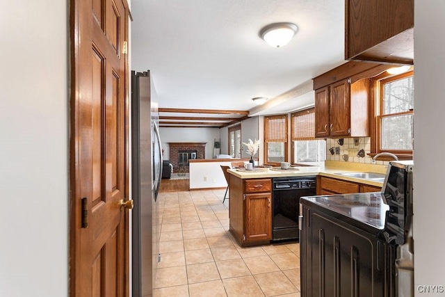 kitchen featuring black dishwasher, light tile patterned floors, freestanding refrigerator, a sink, and a peninsula