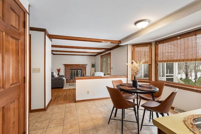 dining area with baseboards, a fireplace, beamed ceiling, and light tile patterned floors