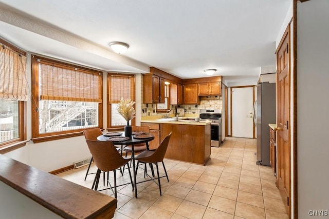 kitchen with stainless steel appliances, tasteful backsplash, visible vents, plenty of natural light, and a peninsula