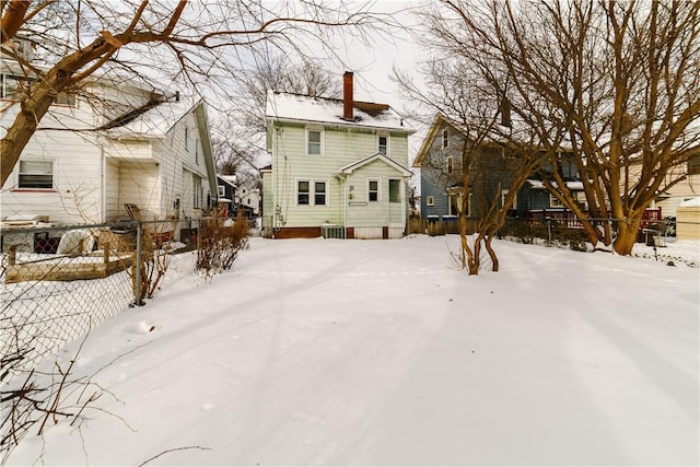 snow covered property with a chimney, fence, and a residential view