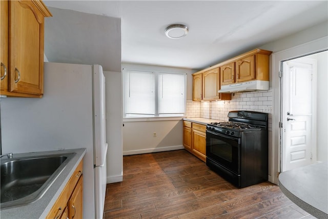 kitchen featuring dark wood-style flooring, tasteful backsplash, gas stove, a sink, and under cabinet range hood