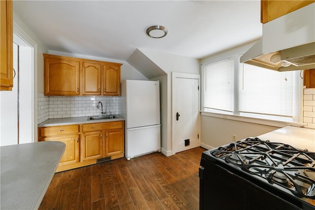 kitchen with dark wood finished floors, freestanding refrigerator, black gas stove, under cabinet range hood, and a sink