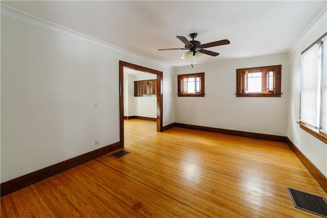 unfurnished room with ornamental molding, light wood finished floors, visible vents, and baseboards