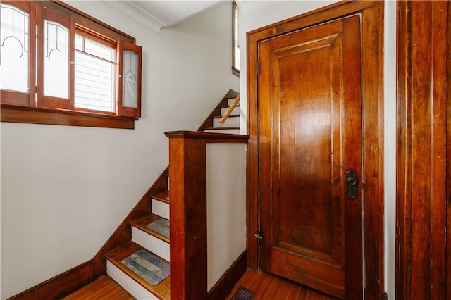 staircase with wood finished floors, visible vents, and baseboards