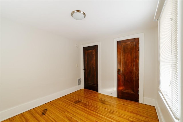 unfurnished bedroom with light wood finished floors, baseboards, and visible vents