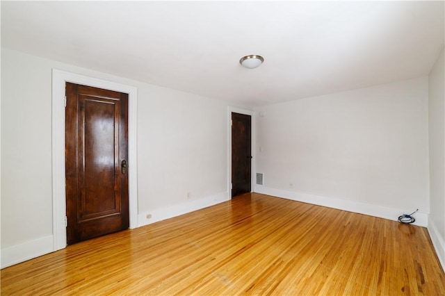 unfurnished room featuring light wood finished floors, visible vents, and baseboards