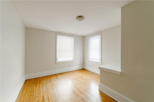 spare room featuring baseboards and wood finished floors