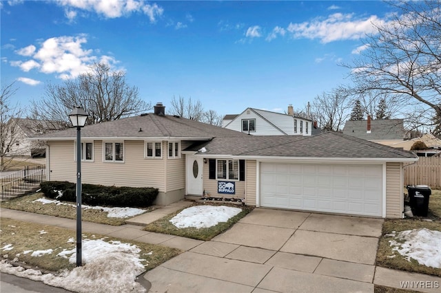 tri-level home featuring driveway, a garage, fence, and roof with shingles