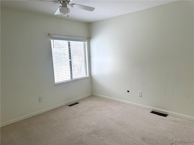 spare room featuring visible vents, light colored carpet, baseboards, and ceiling fan