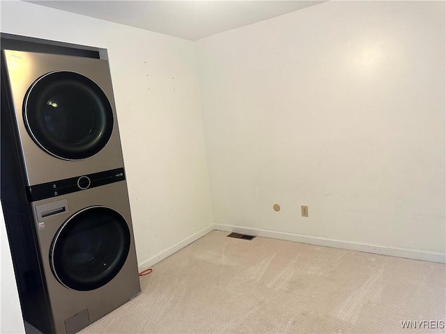 clothes washing area featuring baseboards, carpet, laundry area, and stacked washer / dryer