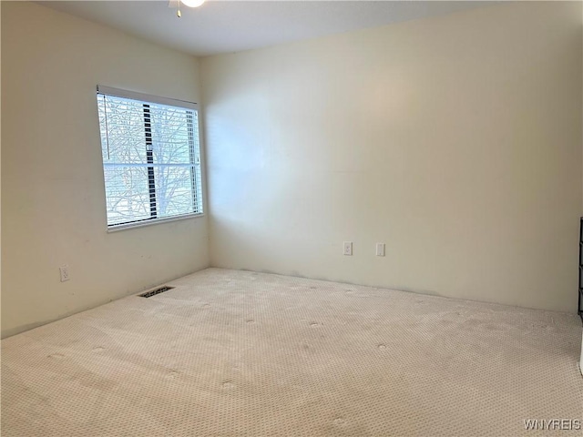 carpeted empty room featuring visible vents