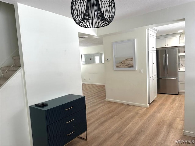 kitchen featuring visible vents, baseboards, light wood-style flooring, freestanding refrigerator, and white cabinets