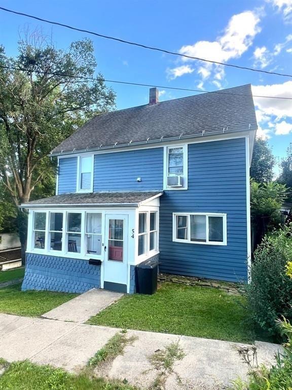 rear view of property featuring roof with shingles, a yard, and a chimney