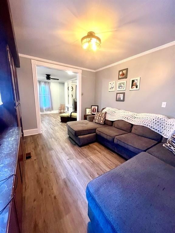 living area with visible vents, crown molding, baseboards, and wood finished floors