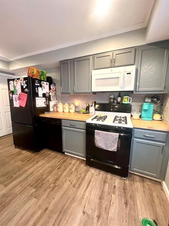 kitchen with light wood-style floors, ornamental molding, gray cabinets, black appliances, and tasteful backsplash