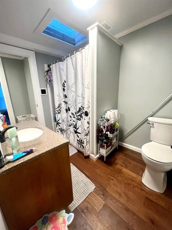 bathroom with baseboards, visible vents, toilet, wood finished floors, and vanity