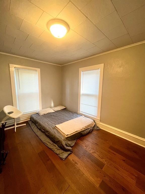 unfurnished bedroom with ornamental molding, dark wood-style flooring, and baseboards