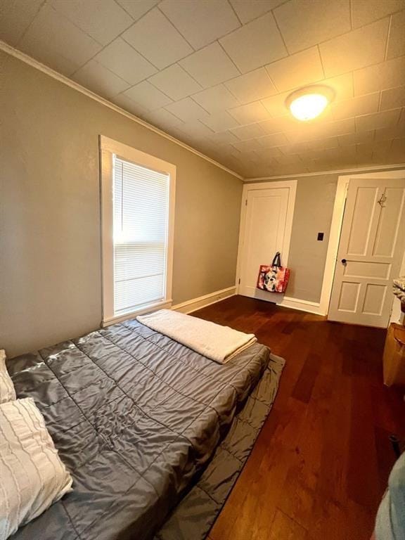 bedroom with dark wood finished floors, crown molding, and baseboards