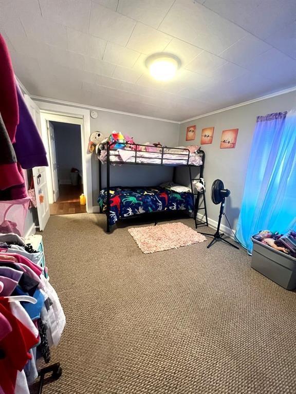 carpeted bedroom featuring ornamental molding and baseboards