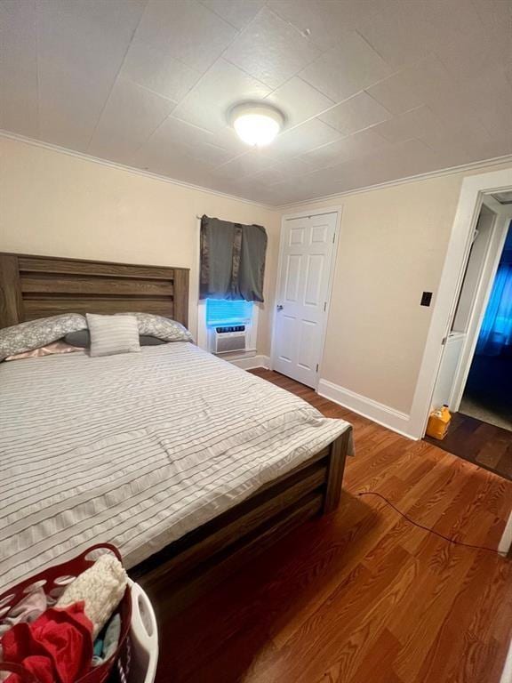 bedroom with cooling unit, baseboards, ornamental molding, and dark wood-type flooring