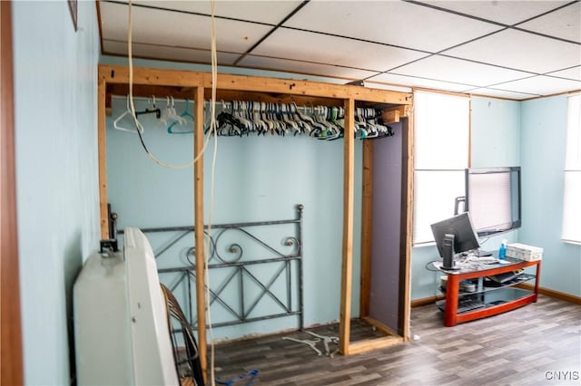 basement featuring wood finished floors, a paneled ceiling, and baseboards