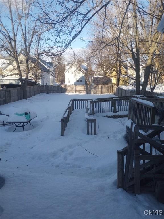 snowy yard with a fenced backyard