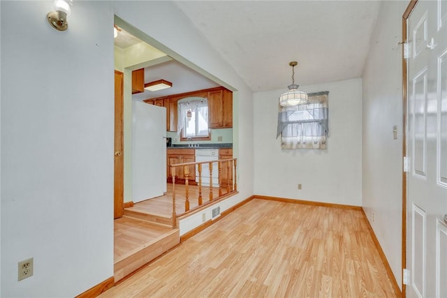 unfurnished dining area with light wood-style floors and baseboards