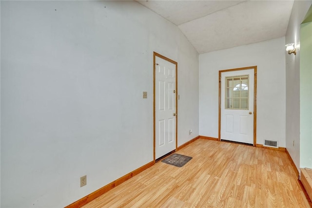 empty room with light wood-style floors, visible vents, and baseboards