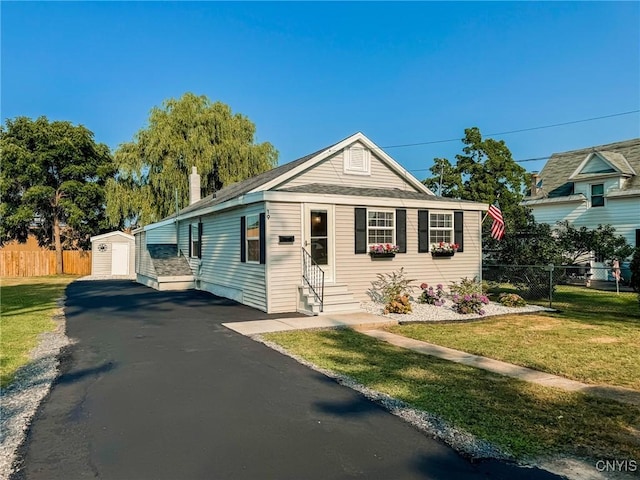 bungalow-style house featuring entry steps, driveway, an outbuilding, and fence