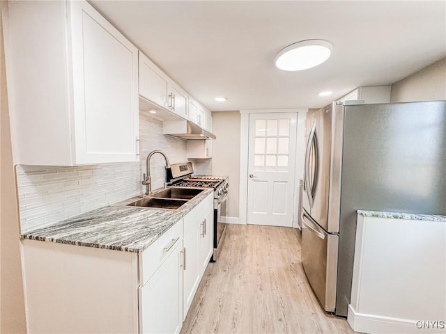 kitchen with tasteful backsplash, stainless steel appliances, light wood-type flooring, white cabinetry, and a sink