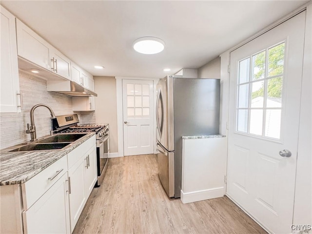 kitchen with light wood finished floors, tasteful backsplash, stainless steel appliances, and a sink