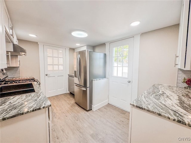 kitchen featuring appliances with stainless steel finishes, light wood-type flooring, white cabinetry, and decorative backsplash