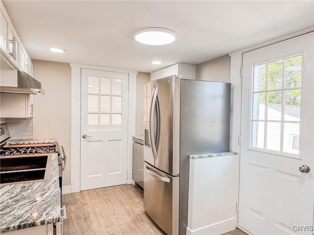 kitchen with appliances with stainless steel finishes, decorative backsplash, light wood-style flooring, and white cabinets