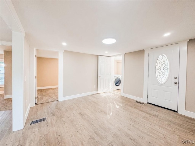 entryway with washer / dryer, baseboards, visible vents, and wood finished floors