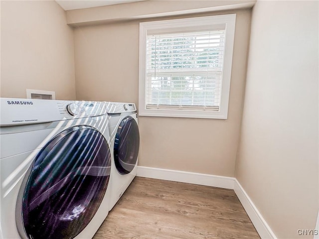 laundry area featuring light wood-style floors, laundry area, washer and clothes dryer, and baseboards