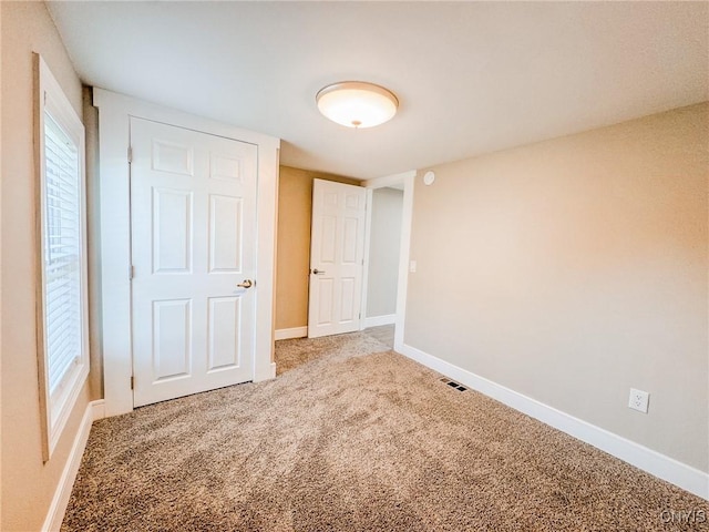 unfurnished bedroom with carpet floors, visible vents, and baseboards