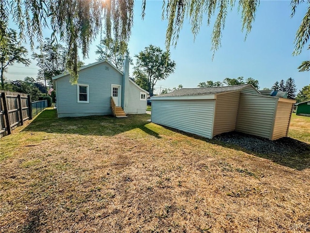 back of house with entry steps, a yard, and fence