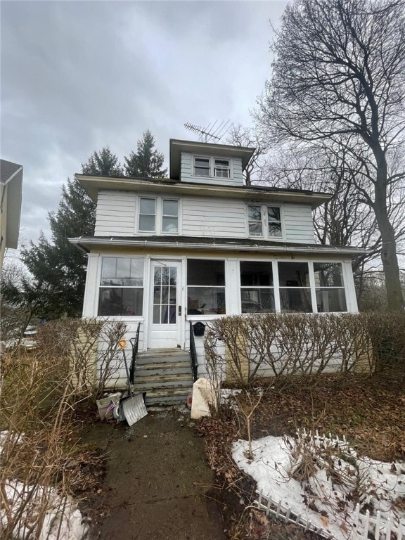 american foursquare style home featuring entry steps and a sunroom