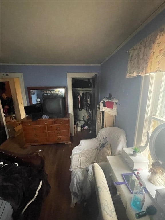 bedroom with ornamental molding, a closet, and wood finished floors