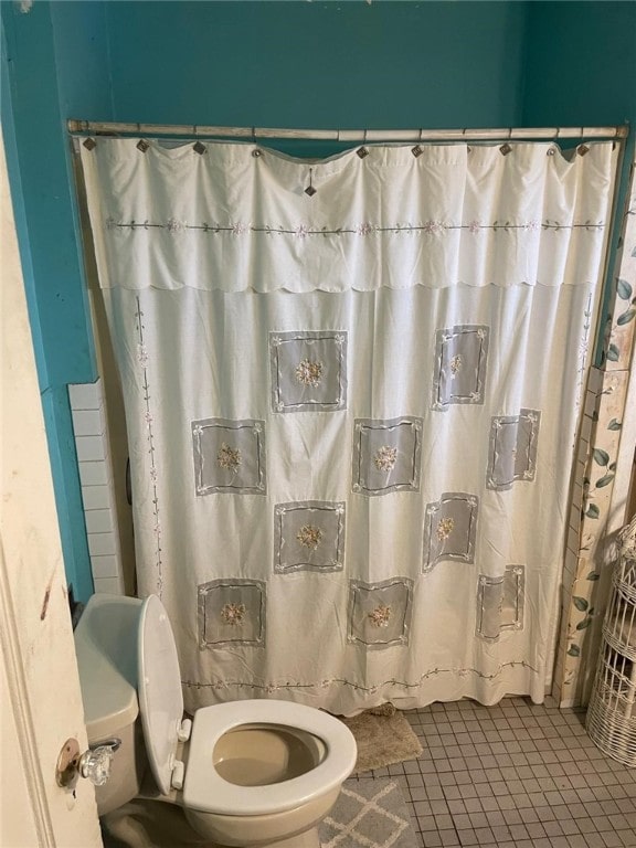 full bath with toilet, a shower with curtain, and tile patterned flooring