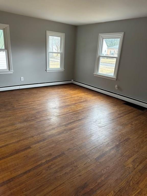 unfurnished room featuring a baseboard heating unit and dark wood-style flooring