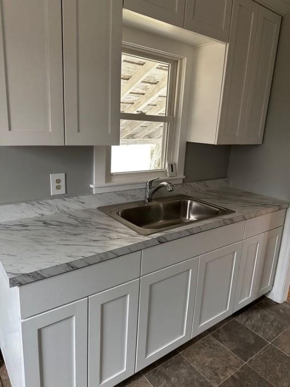 kitchen featuring light countertops, white cabinetry, and a sink