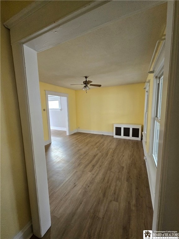 spare room featuring ceiling fan, visible vents, baseboards, and wood finished floors