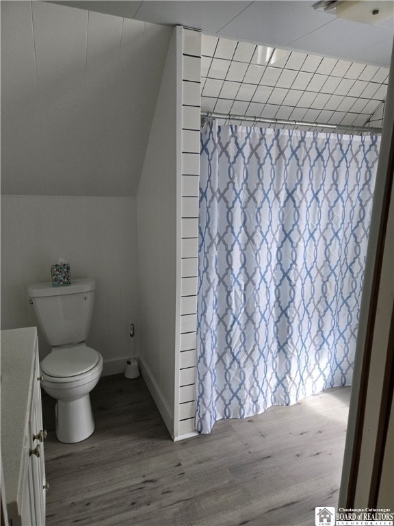 bathroom with toilet, curtained shower, vaulted ceiling, and wood finished floors